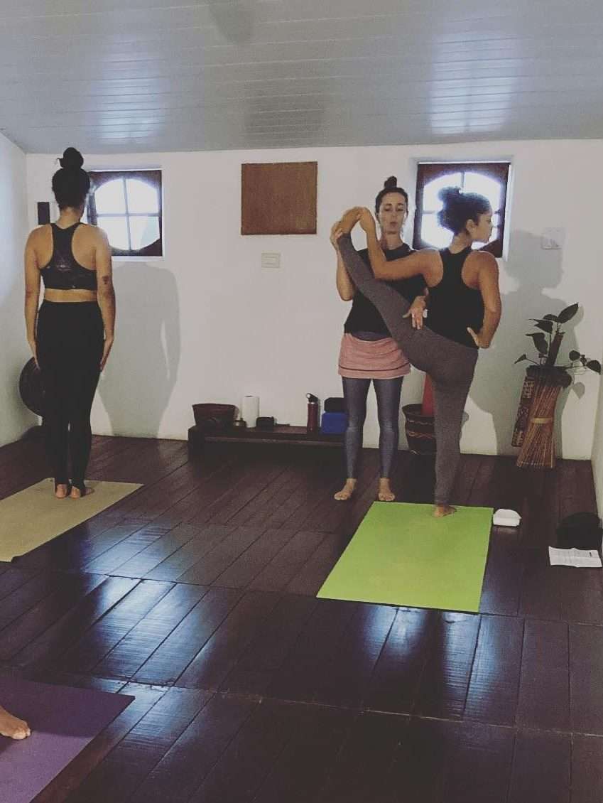 Aula de Yoga com Julia Raboni instrutora de Ashtanga Yoga em Saquarema realizando ajuste na postura de uma aluna