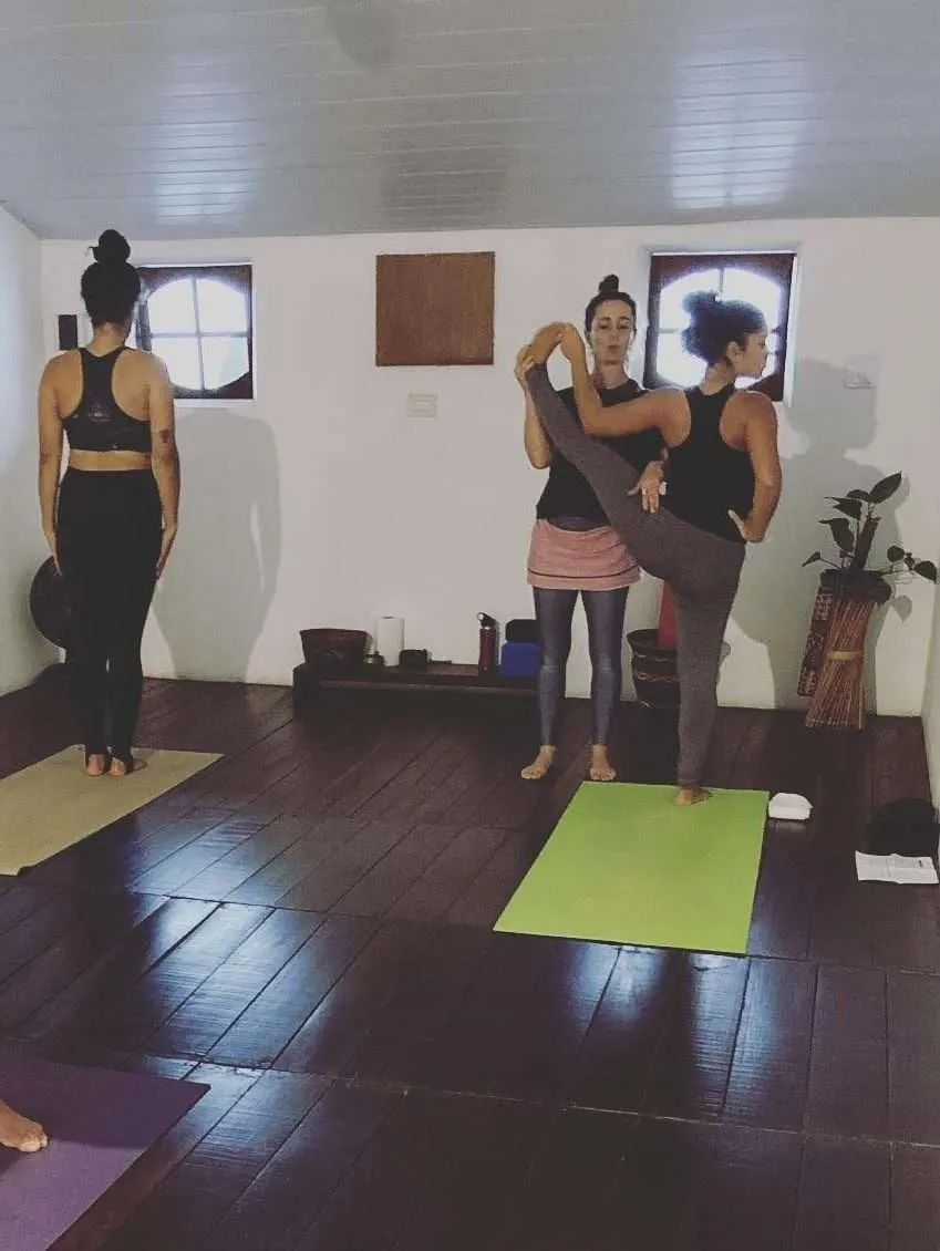 Aula de Yoga com Julia Raboni instrutora de Ashtanga Yoga em Saquarema realizando ajuste na postura de uma aluna