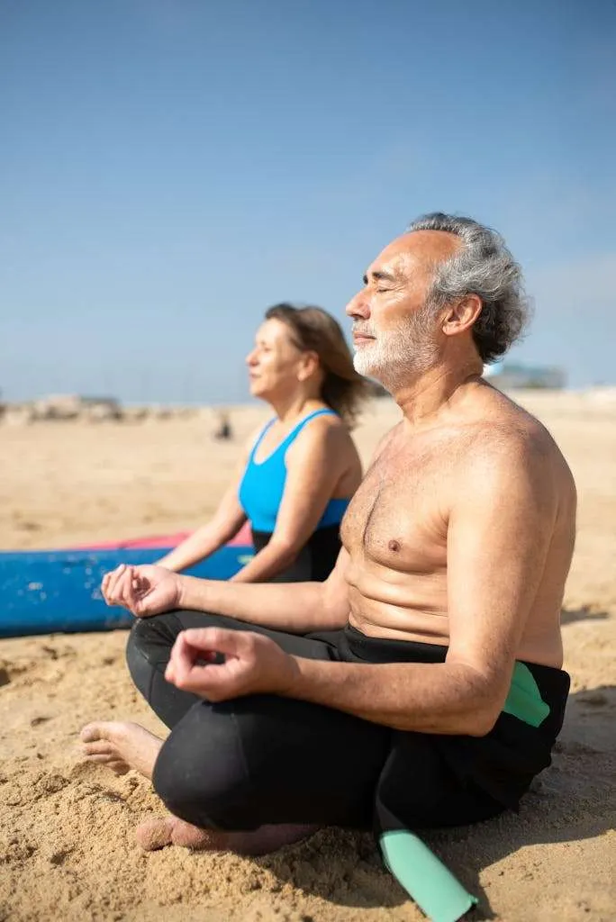 Casal de surfistas praticando yoga na praia