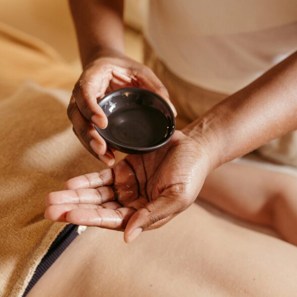 Hands applying massage oil on a client's back in a spa setting for relaxation and rejuvenation.